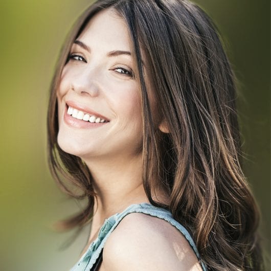 Smiling woman with long dark hair wearing a green tank top.