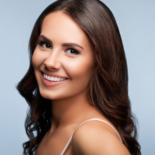 Portrait of beautiful cheerful smiling young woman in front of gray background.